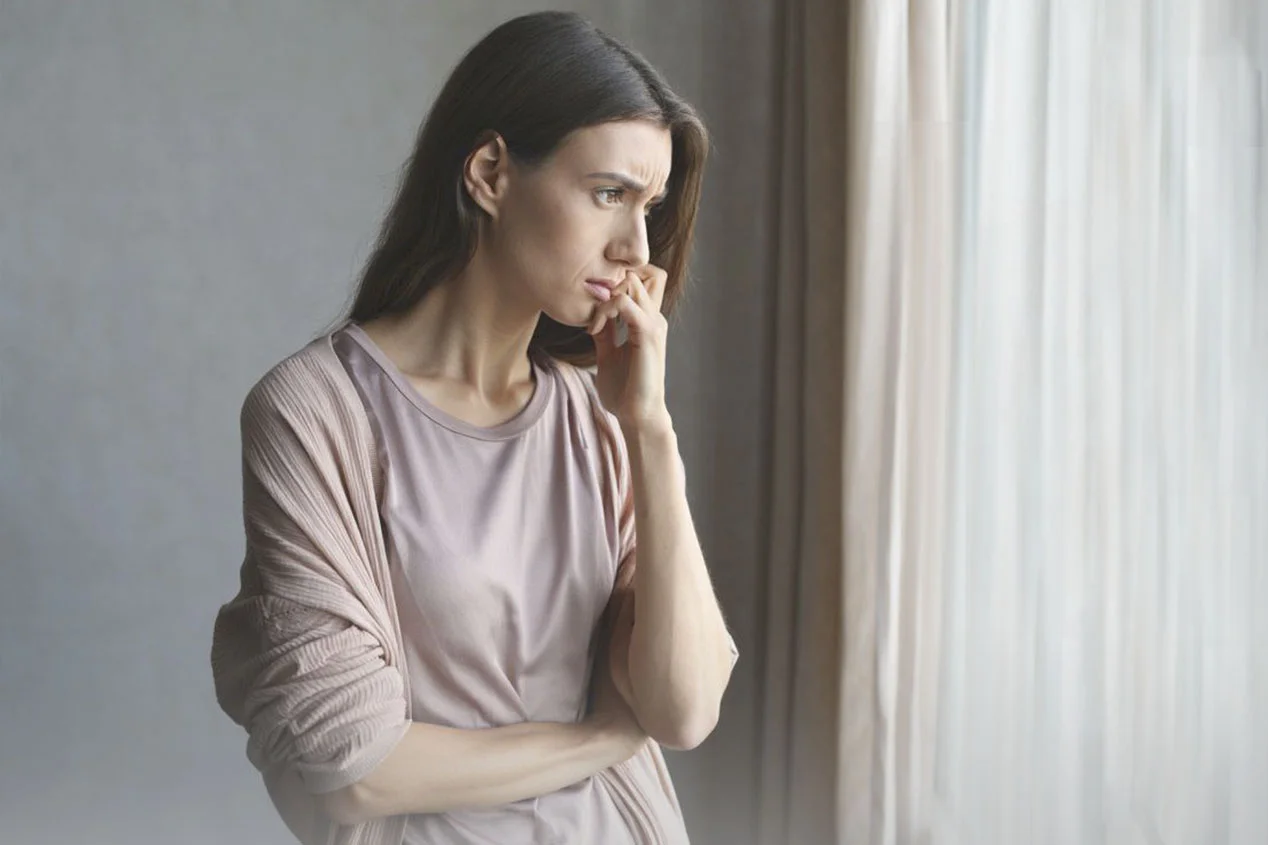 Женщина нервно смотрит в окно